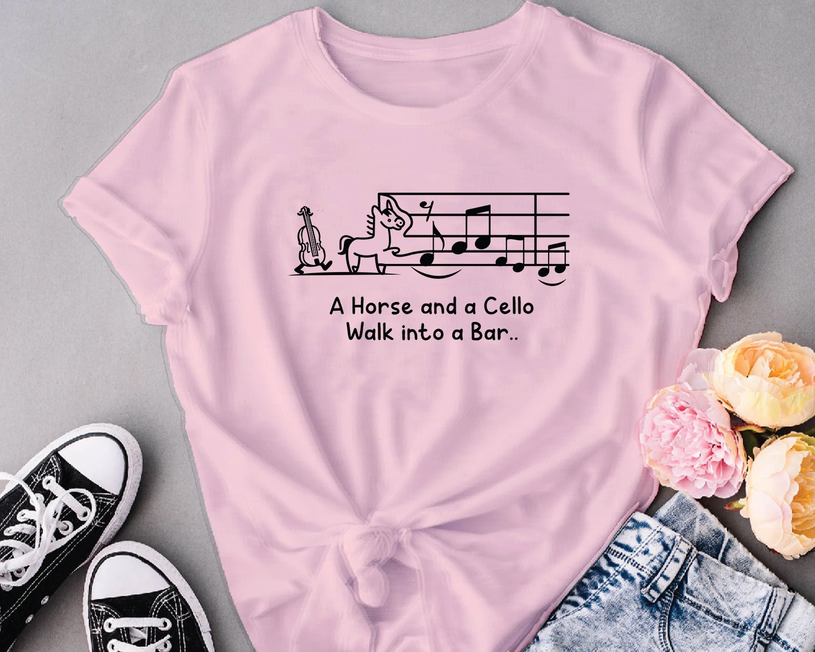 Pink t-shirt with humorous text design on a gray background with sneakers and flowers.